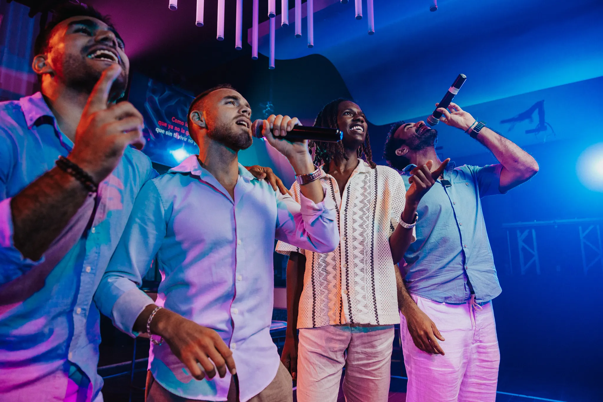 A group of friends singing karaoke under colorful nightclub lighting at Breathless Riviera Cancun’s nightlife venues.
