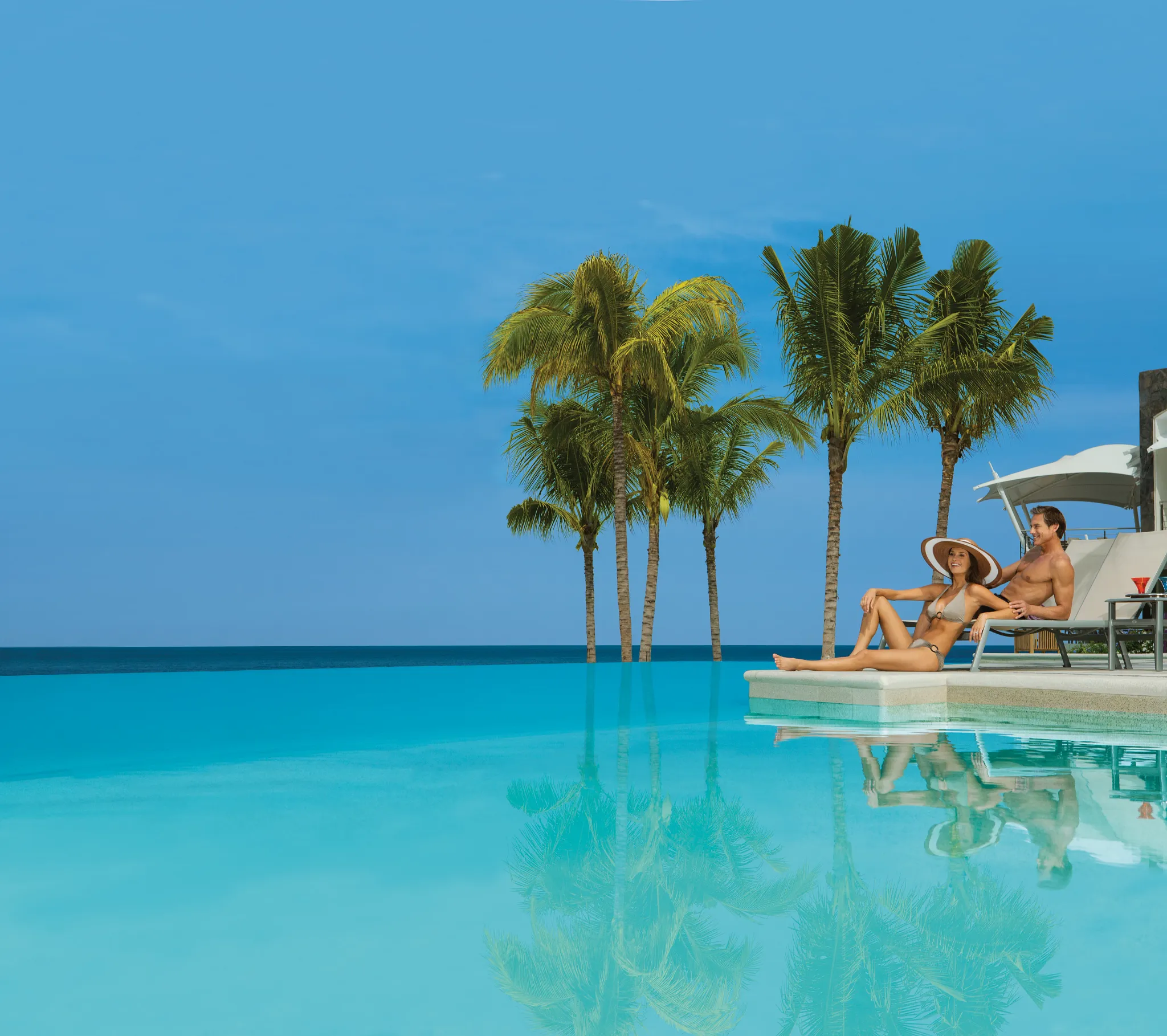 Tropical infinity pool lined with palm trees overlooking the ocean at Secrets Vallarta Bay Puerto Vallarta.